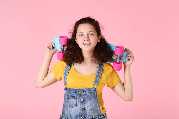 Young girl with skateboard on pink background - Fotó, kép