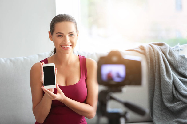 Young female blogger with mobile phone recording video indoors - Photo, Image