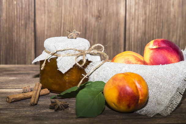 Food, sweet dessert. Homemade canning. A jar of fruit peach jam and fresh ripe peaches on a wooden table background in a rustic style - Fotoğraf, Görsel