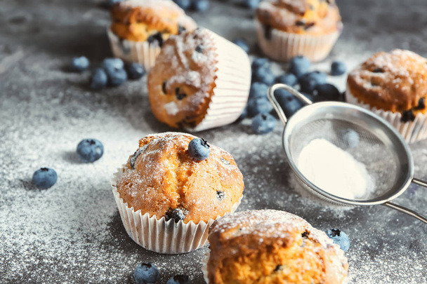 Muffins de mirtilo saborosos com açúcar em pó na mesa cinza
 - Foto, Imagem