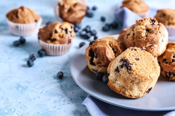 Piatto con gustosi muffin ai mirtilli sul tavolo di colore
 - Foto, immagini