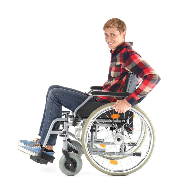 Νεαρός άνδρας κάθεται στο αναπηρικό αμαξίδιο σε λευκό φόντο - Φωτογραφία, εικόνα