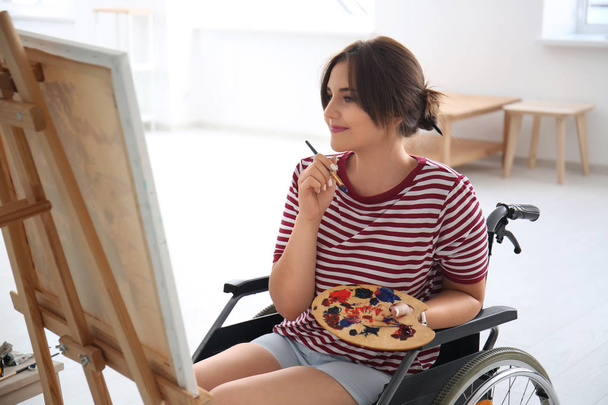 Giovane artista donna in sedia a rotelle quadro pittura a casa
 - Foto, immagini