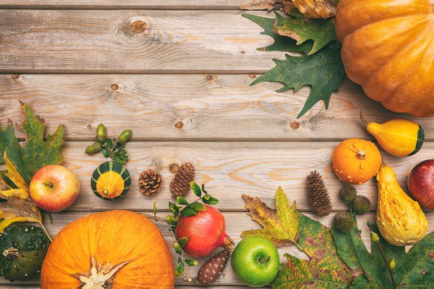 Thanksgiving concept. Colorful pumpkins, fruits and fall leaves on rustic wooden background, copy space, top view - Photo, Image