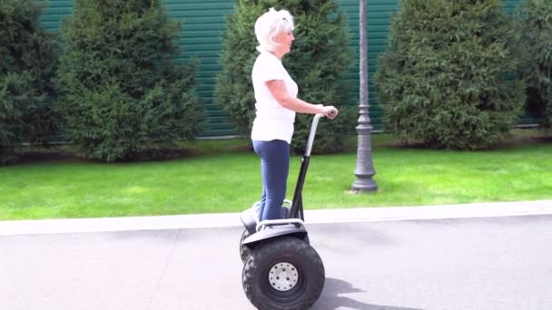 Woman riding a Electric Personal Transporter along a street - Filmati, video