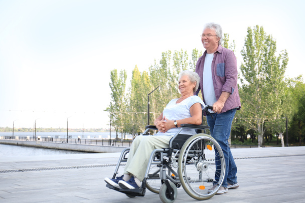 Senior Kobieta w wózku inwalidzkim wraz z mężem na zewnątrz - Zdjęcie, obraz