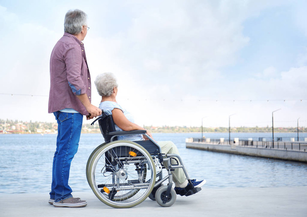 Seniorin im Rollstuhl und ihr Mann in der Nähe des Flusses - Foto, Bild