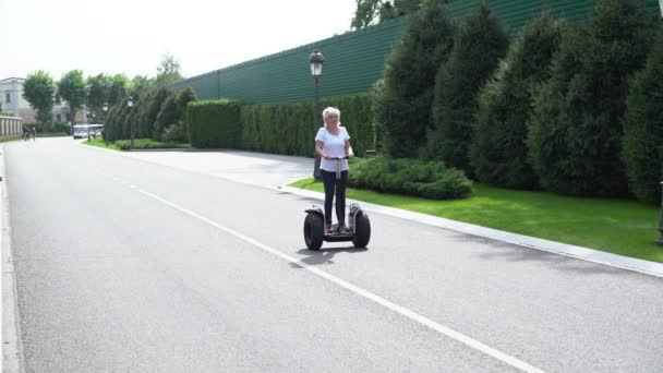 Woman riding past the camera on a Electric Personal Transporter - Materiał filmowy, wideo