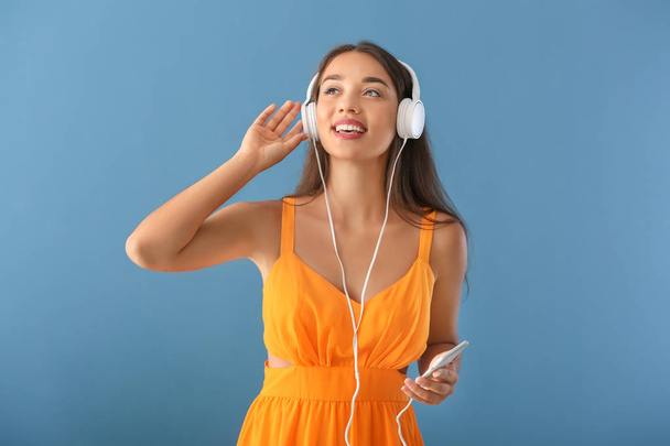 Beautiful young woman listening to music on color background - Photo, Image
