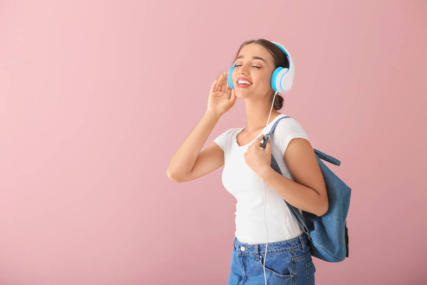 Kaunis nuori nainen kuuntelee musiikkia värillinen tausta - Valokuva, kuva
