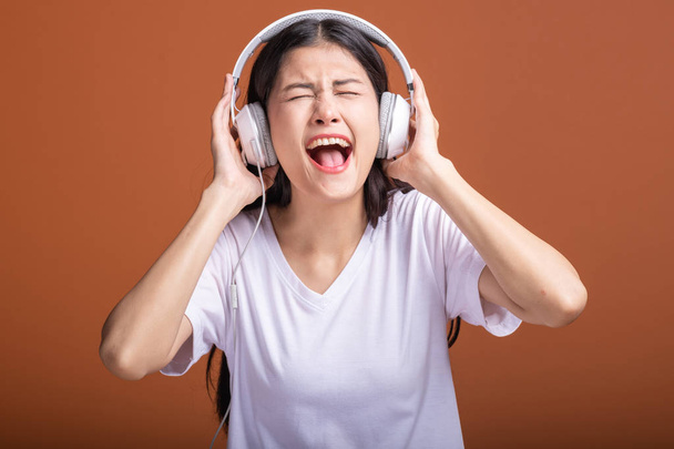 Woman using headphone isolated over orange background. Young asian woman listen to music with head phone, extremely excited mood. Hipster lifestyle concept, - Fotoğraf, Görsel