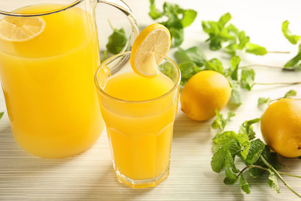 ガラスと光の木製テーブルに新鮮なレモン汁の水差し - 写真・画像