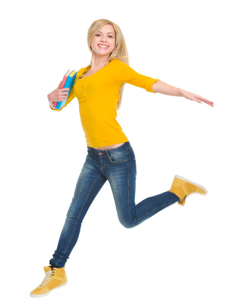 Smiling student girl with books jumping - Фото, изображение