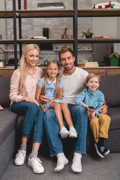 happy young family sitting on couch together and looking at camera - Фото, зображення