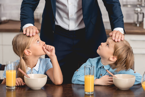 朝食時に彼らの額に触れることによって彼の病気の子供の温度を調べてショットの fo 父をトリミング - 写真・画像