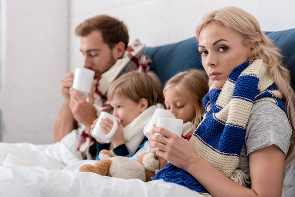 diseased young family drinking warming beverages in bed - Photo, image
