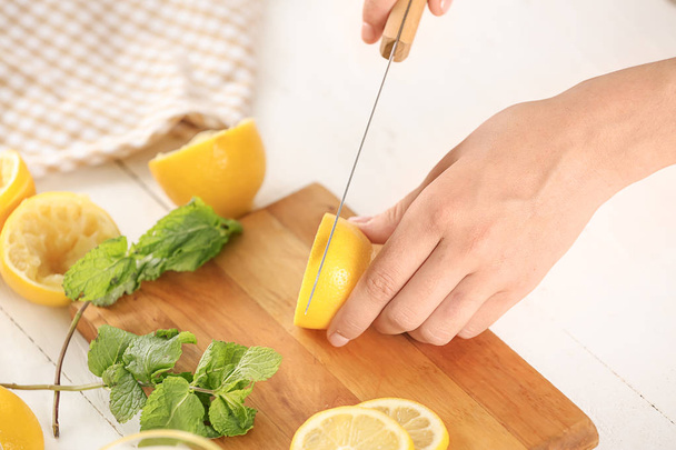 Mulher cortando limão fresco para suco na mesa
 - Foto, Imagem