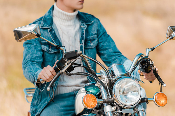 обрезанный вид стильного молодого человека на ретро мотоцикле
 - Фото, изображение