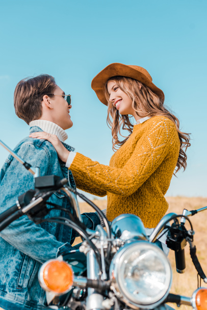 smiling couple looking at each other and sitting on motorbike - Foto, imagen