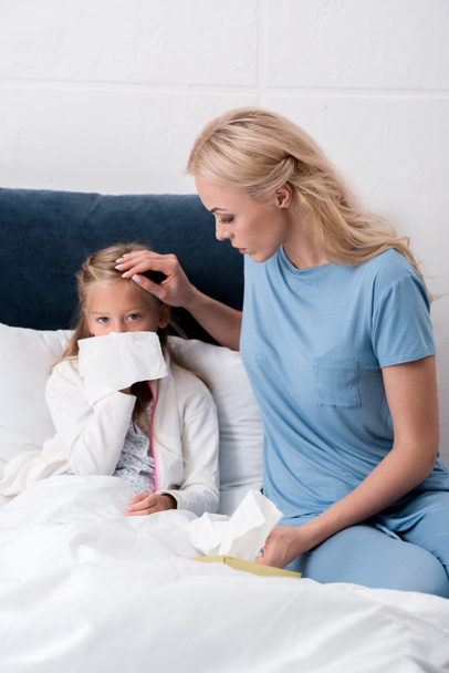 giovane madre prendersi cura di sua figlia mentre soffia il naso
 - Foto, immagini