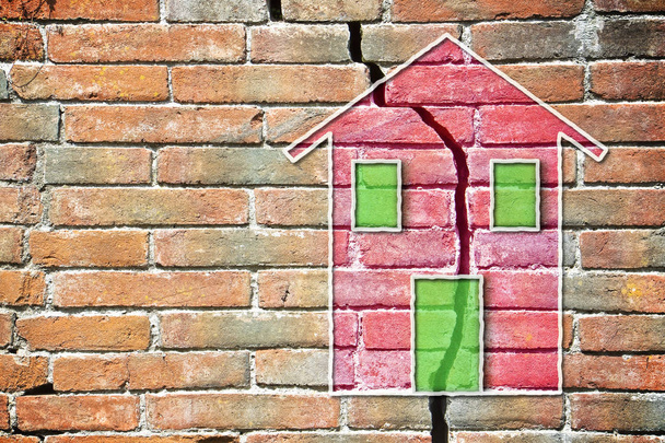 Gebarsten bakstenen muur met een gekleurde huis getrokken op het - Foto, afbeelding