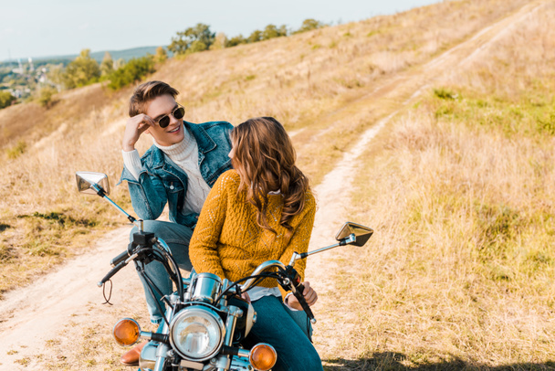couple sitting on retro motorbike and looking at each other - Foto, Imagem