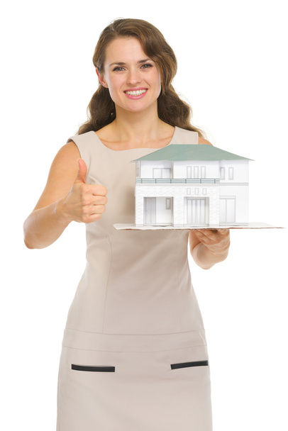 Woman landlord with scale model of house showing thumbs up - Foto, Imagen