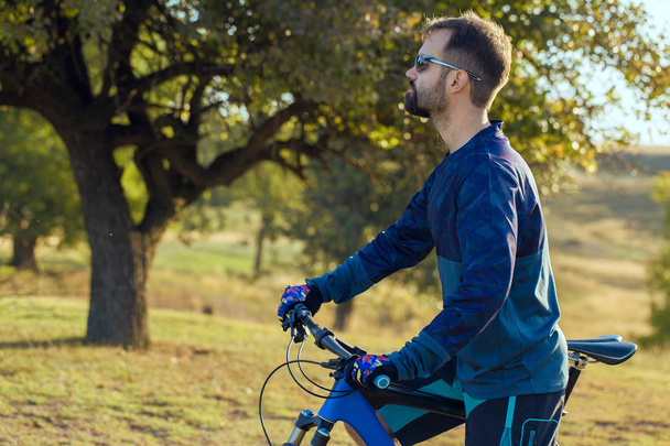 Ciclista en pantalones cortos y jersey en una moderna bicicleta rígida de carbono con horquilla de suspensión neumática
 - Foto, imagen