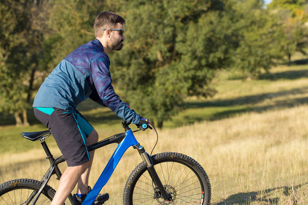 Ciclista em shorts e jersey em uma bicicleta moderna hardtail de carbono com um garfo de suspensão pneumática
 - Foto, Imagem