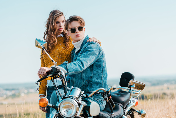 young girlfriend hugging boyfriend while sitting on vintage motorbike - Valokuva, kuva