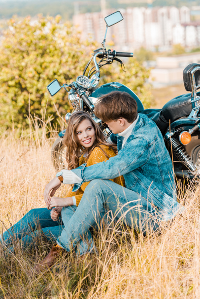 νεαρό ζευγάρι κάθεται κοντά vintage μοτοσικλέτα και βλέπουν ο ένας τον άλλον - Φωτογραφία, εικόνα