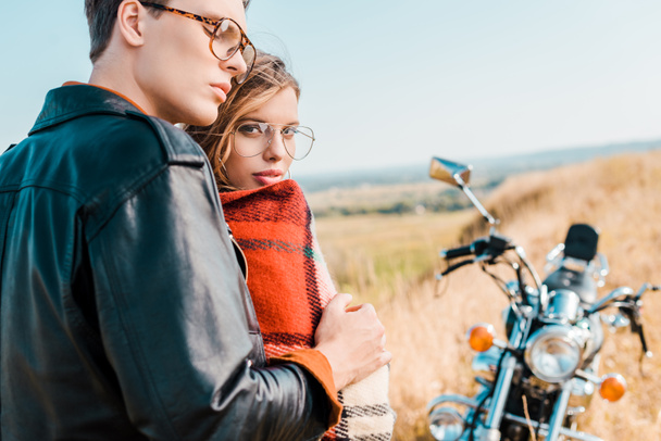 young couple in glasses standing near vintage motorbike - Foto, afbeelding