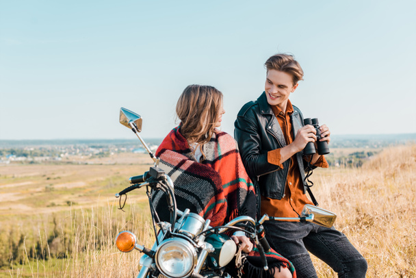 young boyfriend holding binoculars near girlfriend sitting on motorbike  - Photo, Image