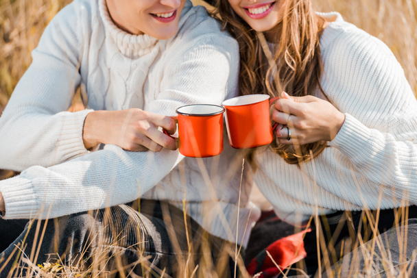cropped view of young couple holding cups on rural meadow - Foto, Bild