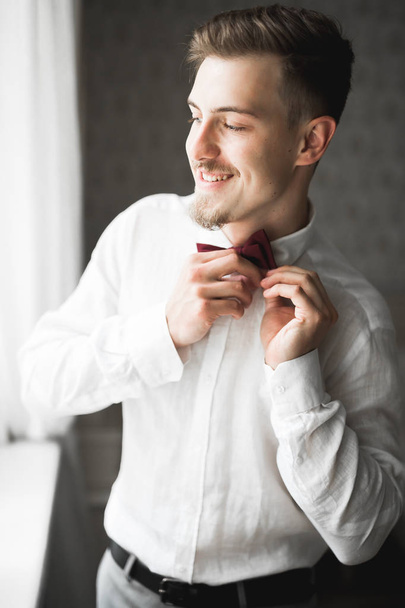 Grooms morning preparation. Handsome man getting dressed and preparing for the wedding - Foto, afbeelding