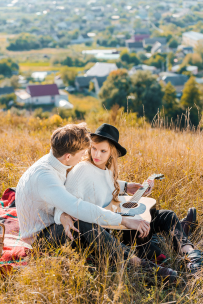 smiling couple resting on meadow while young man holding guitar - Photo, image