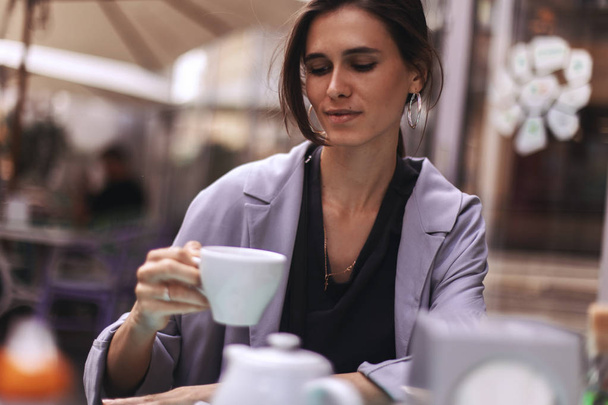 attraktive brünette Bussines Frau mit Schwanz trinkt Kaffee oder Tee im Restaurant. Kaffeepause - Foto, Bild
