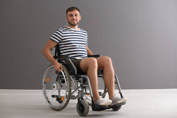 Young man in wheelchair against grey wall - Φωτογραφία, εικόνα