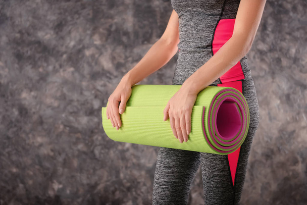 Young woman with yoga mat on grey background - Photo, Image