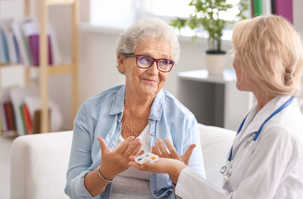 Arzt gibt Seniorin zu Hause Medikamente - Foto, Bild