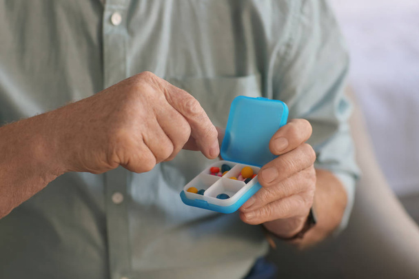 Senior man holding container with pills, closeup - Фото, изображение
