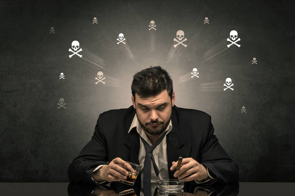 Пьяный человек сидит за столом с концепцией черепов
 - Фото, изображение