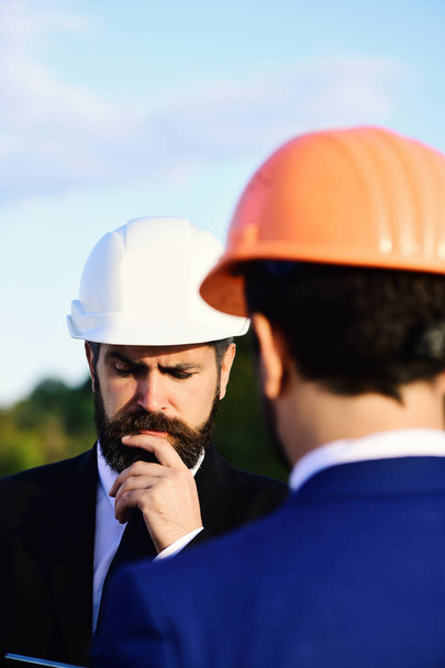 Worker and engineer hold meeting. Architect with puzzled face - Foto, afbeelding