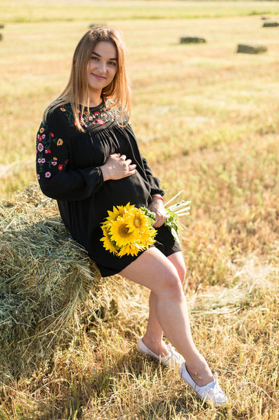 Pregnant girl in sunflowers, happy girl waiting for the baby - 写真・画像