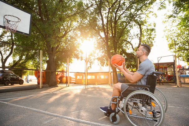 Joven en silla de ruedas jugando al baloncesto al aire libre
 - Foto, Imagen