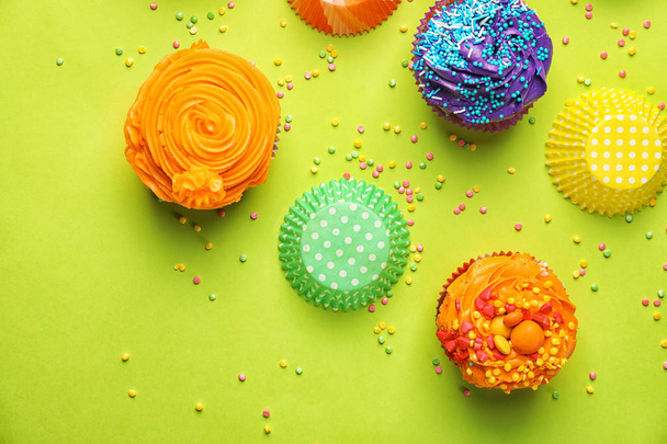 Ízletes cupcakes sprinkles és sütő csésze a háttér színe - Fotó, kép