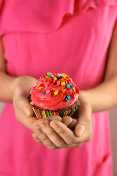 Mujer sosteniendo sabroso cupcake con aspersiones, primer plano
 - Foto, imagen