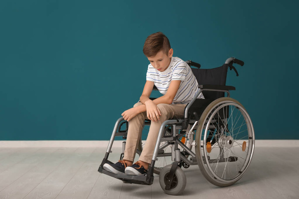 Depressed boy in wheelchair against color wall - Photo, Image