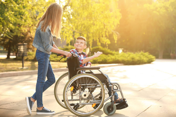 Boy in wheelchair and his sister outdoors - Φωτογραφία, εικόνα