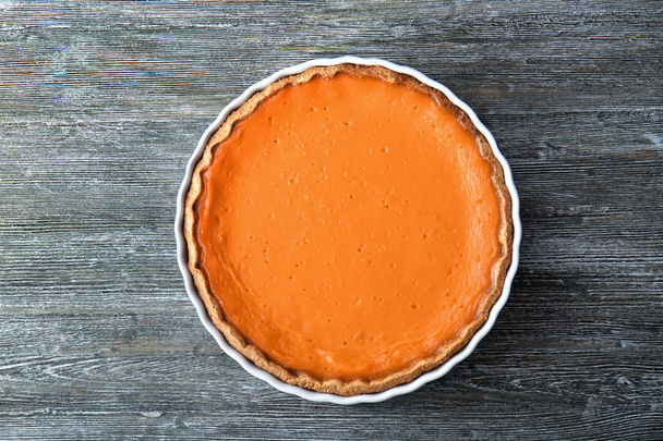 Baking dish with tasty pumpkin pie on wooden table - Foto, afbeelding